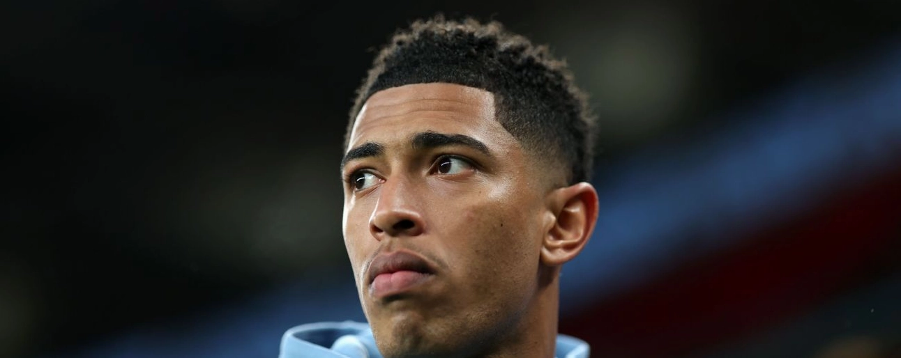 Một cầu thủ bóng đá ngồi trên khán đài theo dõi trận đấu của đội nhà