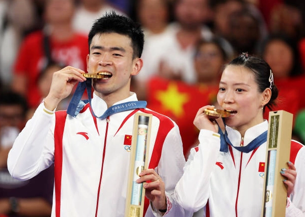 Cặp đôi vô địch Zheng Siwei và Huang Yaqiong cắn huy chương vàng trên bục vinh quang