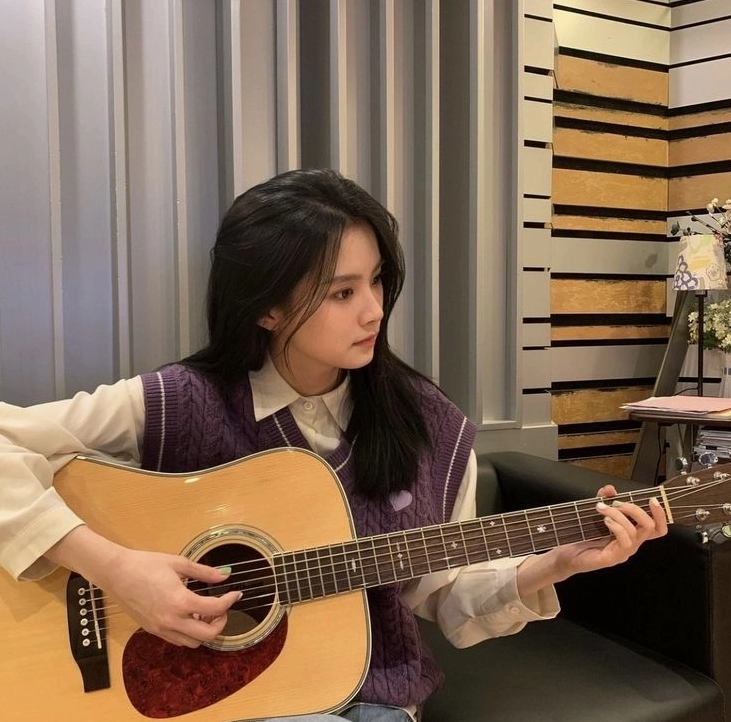 Cô gái xinh đẹp đang tập trung chơi đàn guitar từng bước cải thiện kỹ năng âm nhạc