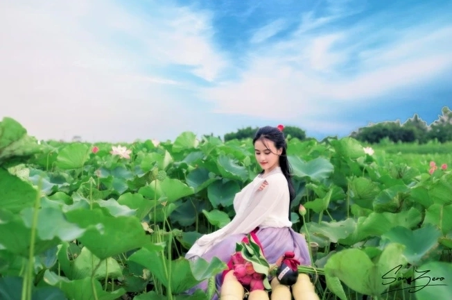 Cô gái xinh đẹp trong trang phục cổ trang ngồi suy tư thả dáng mộng mơ bên hồ sen