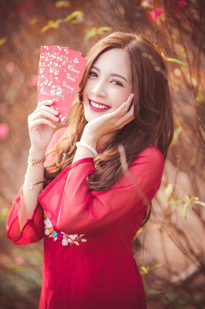 Cô nữ sinh thanh lịch mặc áo dài tạo dáng thướt tha bên cành hoa đào mùa xuân đón Tết