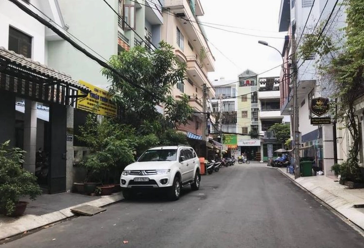 Một hẻm lớn và có 1 chiếc ô tô đậu trên lòng đường
