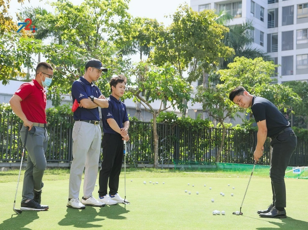 Một học viên đang được huấn luyện viên hướng dẫn cách chơi golf