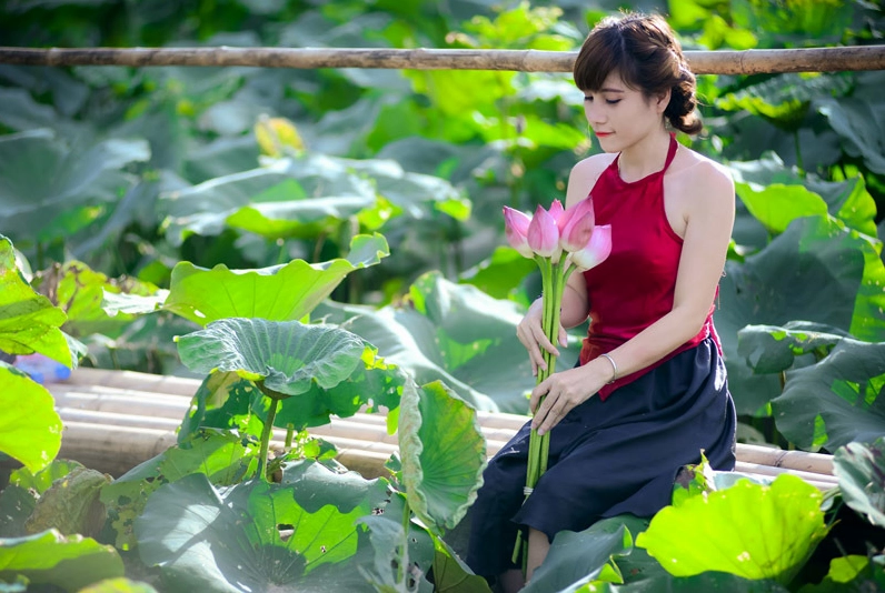 Người đẹp mặc áo yếm truyền thống tạo dáng gợi cảm bên cánh sen mỏng manh