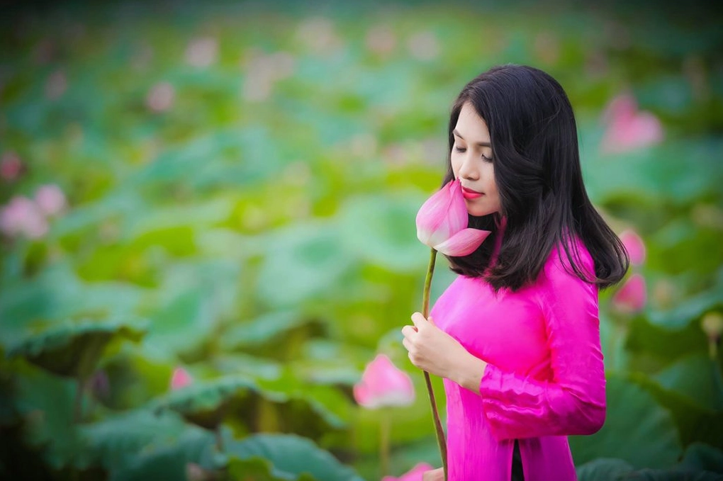 Thiếu nữ mặc áo dài trắng tinh khôi tay cầm hoa sen duyên dáng
